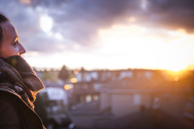 Woman looking at sunset from top of building in the city