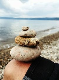 Close-up of stone stack on man leg at beach