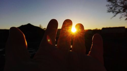 Close-up of silhouette hand against sky during sunset