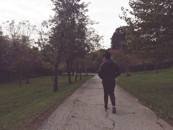 Full length rear view of man walking on footpath