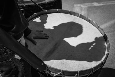 Midsection of man with drum while standing on road