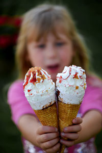 Portrait of girl showing ice cream cones while standing at park