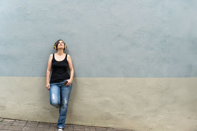 Portrait of young woman standing against wall