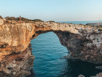 Rock formations by sea against clear sky