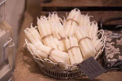 Bundle of candles in basket with price tag on sack at market