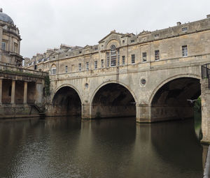 Arch bridge over river against buildings