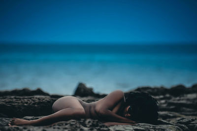 Woman lying on beach against sky