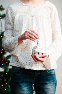 Midsection of woman holding christmas ornament while standing at home