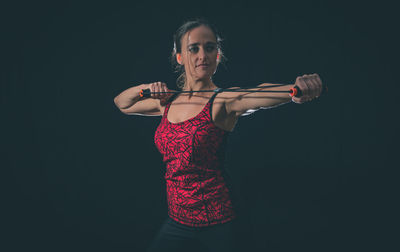 Woman exercising with resistance band against black background