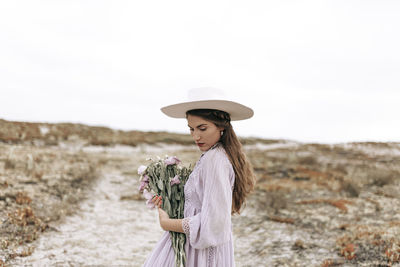 Woman wearing hat standing on land against sky