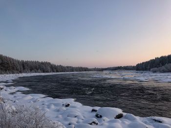 Scenic view of snow covered land against clear sky during winter