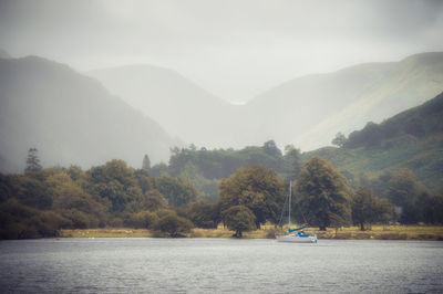 Scenic view of river by mountains against sky