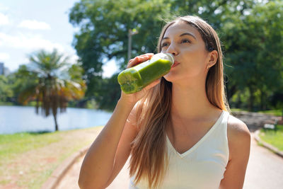 Portrait of smiling young woman drinking water