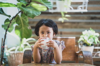 Portrait of girl drinking  milk on table