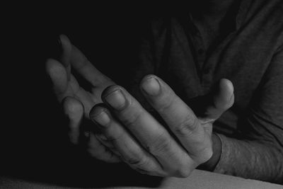 Midsection of man praying in darkroom