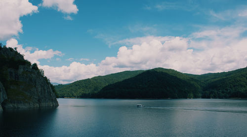 Scenic view of sea by mountains against sky