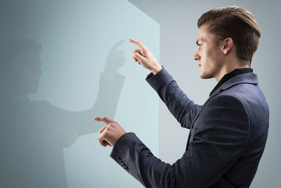 Side view of young man looking at camera against wall