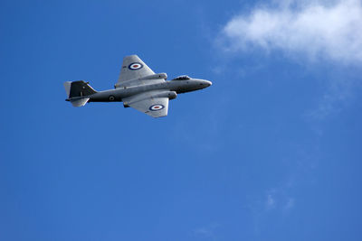 Low angle view of airplane flying against blue sky