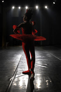 Full length of senior woman standing in illuminated stage