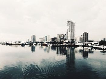 Modern cityscape by sea against sky