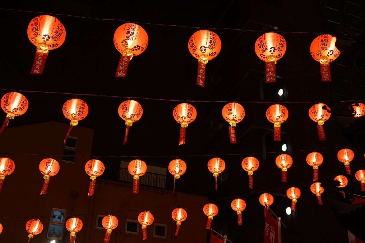 LOW ANGLE VIEW OF ILLUMINATED LANTERNS HANGING IN ROW