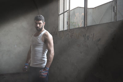 Portrait of muscular man standing against wall