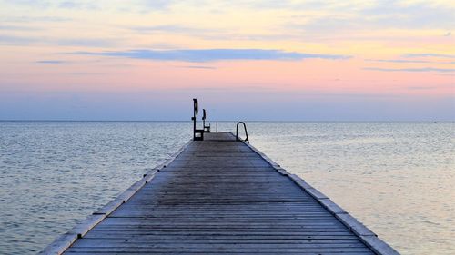 Pier over sea against sky during sunset