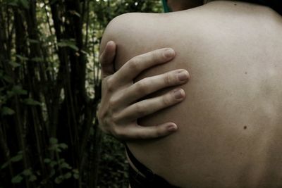 Close-up of woman touching hand against blurred background