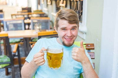 Portrait of smiling young man holding drink at restaurant