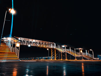 Illuminated bridge over river against sky at night