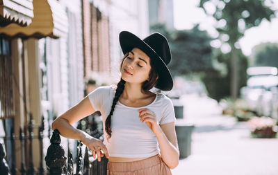 Young woman looking away while standing outdoors