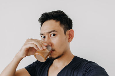 Young woman drinking milk against white background