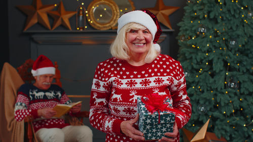 Portrait of senior woman holding christmas gift at home