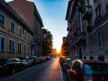 Cars on city street amidst buildings against sky