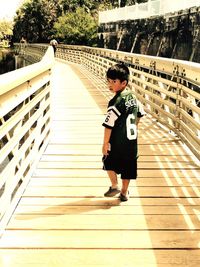 Full length of young woman walking on boardwalk