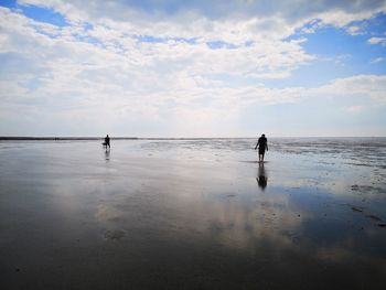 People standing on beach against sky