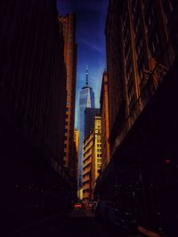 Illuminated street amidst buildings in city at night