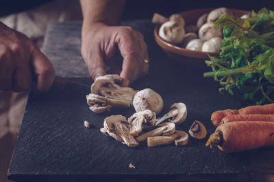 Cropped image of chef cutting mushroom