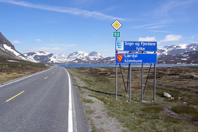 Road signs with snowcapped mountains in background against blue sky