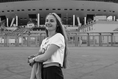 Portrait of smiling young woman standing in city