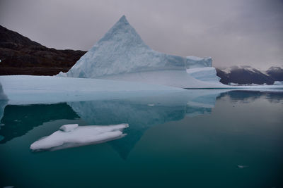 Scenic view of iceberg shapes and reflectins in mirror-like sea in greenland scoresby sound