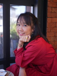 Portrait of smiling young woman sitting on window