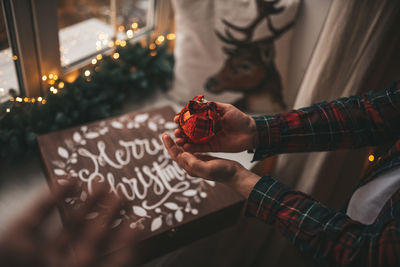 Midsection of man holding christmas decoration at home