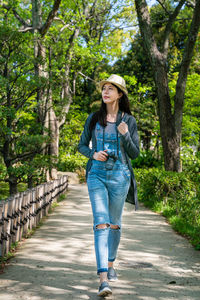Full length of young woman standing on footpath