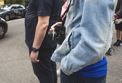 Midsection of woman with digital camera standing on street