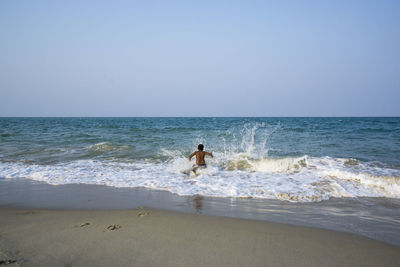 Man standing on beach against clear sky