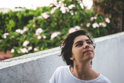 Thoughtful woman looking up against plants