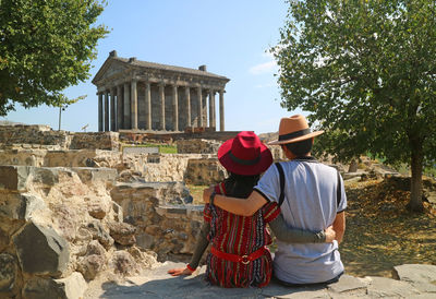 Rear view of couple wearing hats sitting outdoors