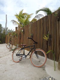 Bicycle parked by fence against sky