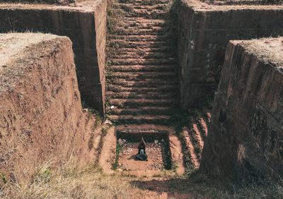 High angle view of man meditating while sitting by old steps